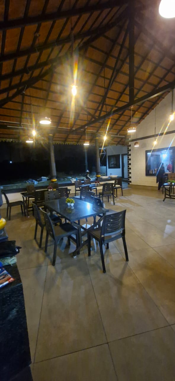A spacious modern restaurant with wood panels, hanging lights, plants at Aqua Terra Villas - Belur, Sakleshpur