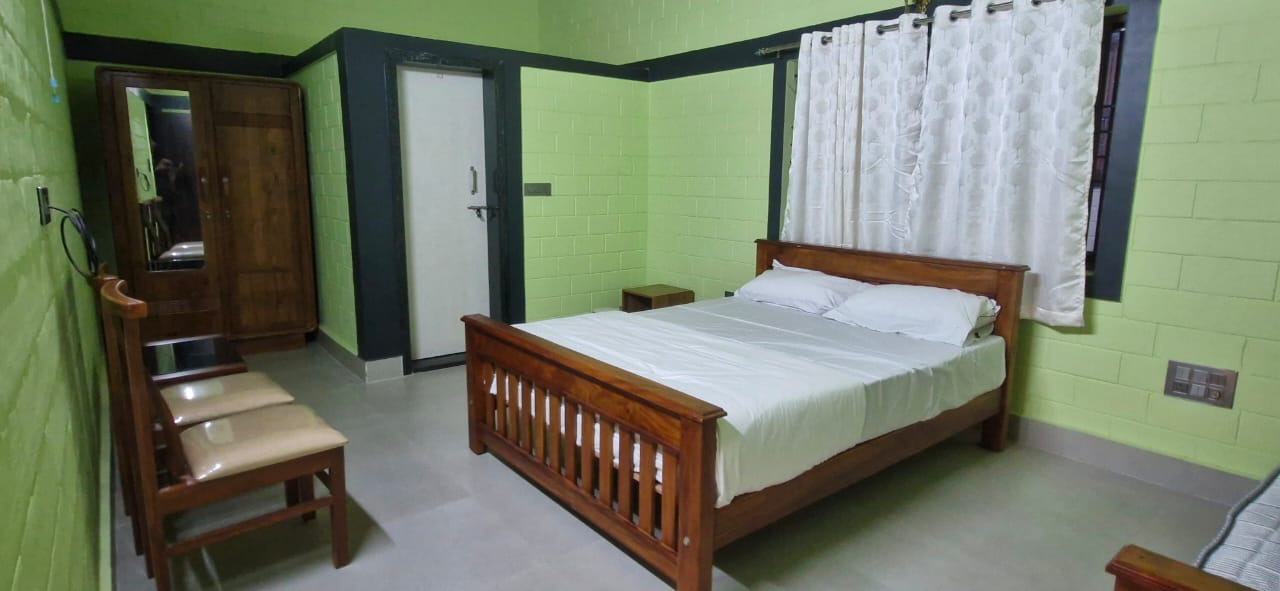 A wooden bed with a white comforter and pillows in a room at Aqua Terra Villas - Belur, Sakleshpur