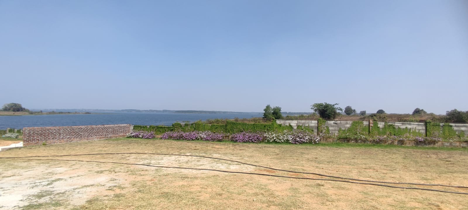 Brick wall overlooking a calm body of water at Aqua Terra Villas - Belur, Sakleshpur