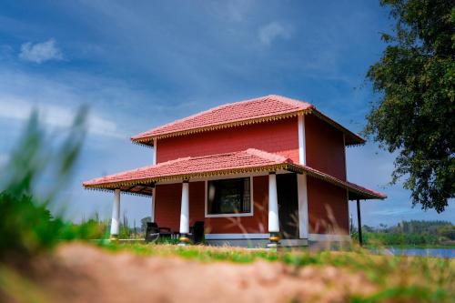 Red two-story building with porch and white pillars at Aqua Terra Villas - Belur, Sakleshpur