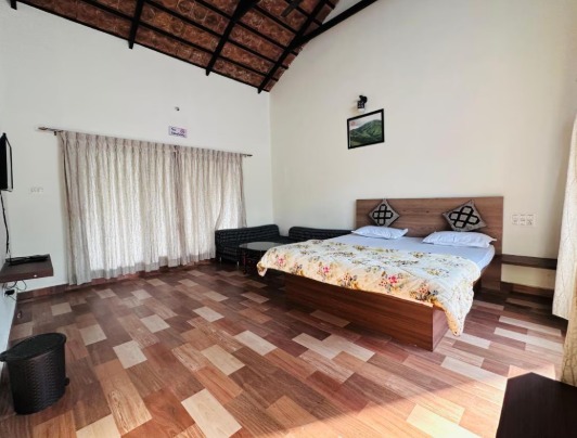 Bed with floral comforter and pillows in a room at Janani Ecostay - Chikmagalur